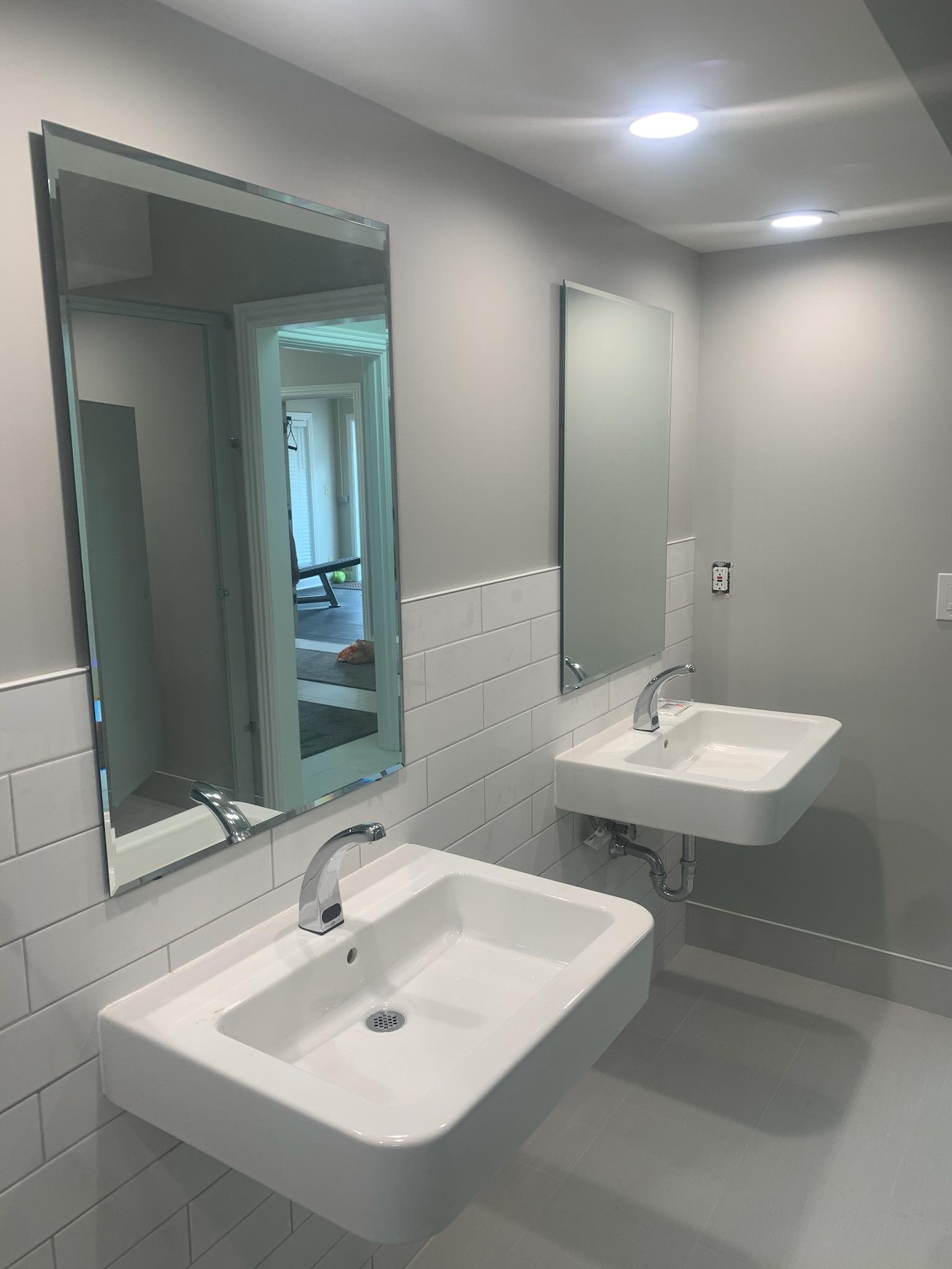 Two white sinks with chrome faucets and mirrors in a bathroom.
