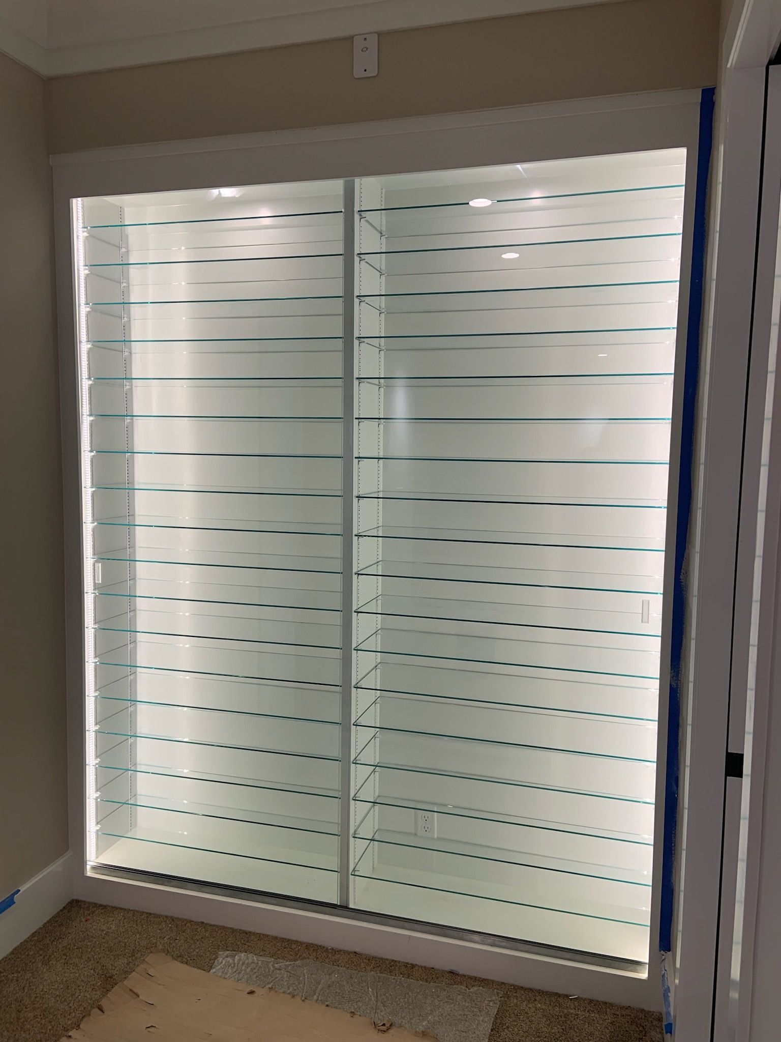 Frosted glass closet doors with horizontal lines, framed in white, inside a room.