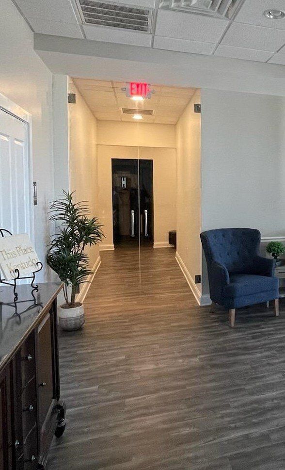 Hallway with wood floor, dark blue armchair, and glass doors.