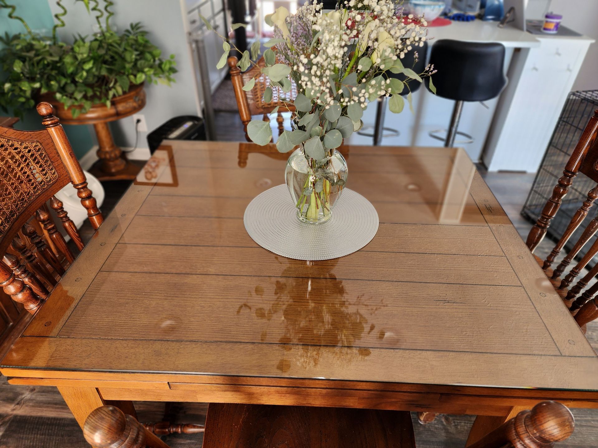 Wooden dining table with spilled liquid and a flower vase.
