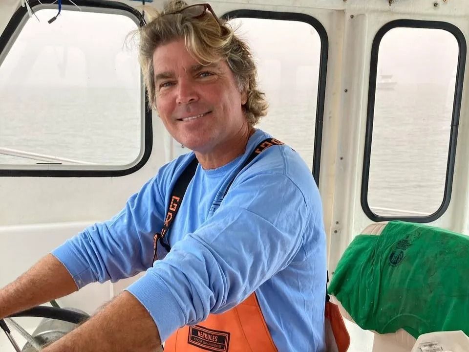 A man in a blue shirt is driving a boat