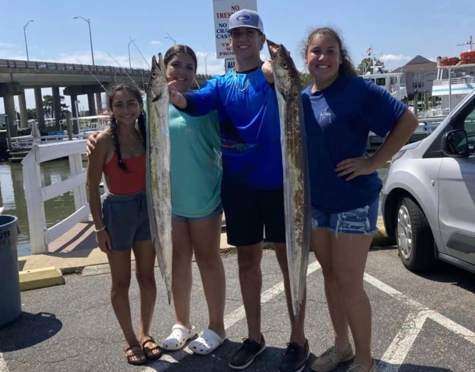 A group of people standing next to each other holding fish.