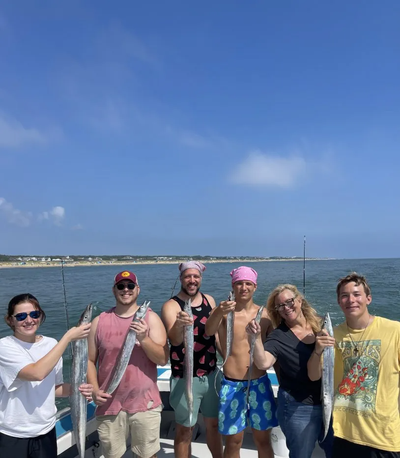 A group of people standing on a boat holding fish