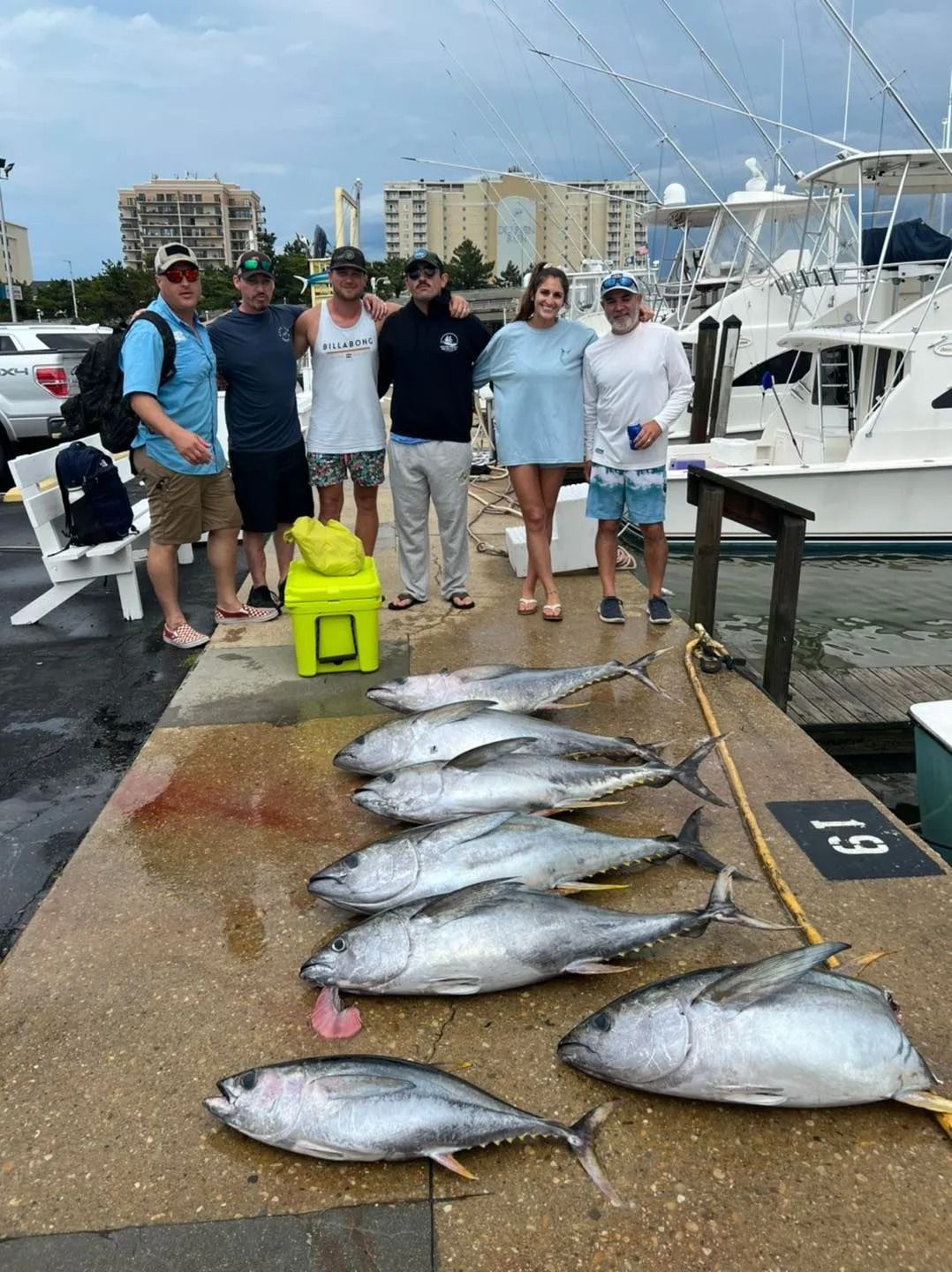 A group of people are standing on a dock with a bunch of fish.