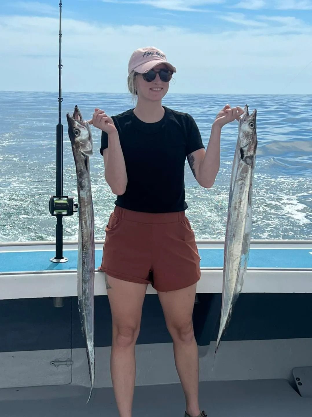 A woman is standing on a boat holding two fish.