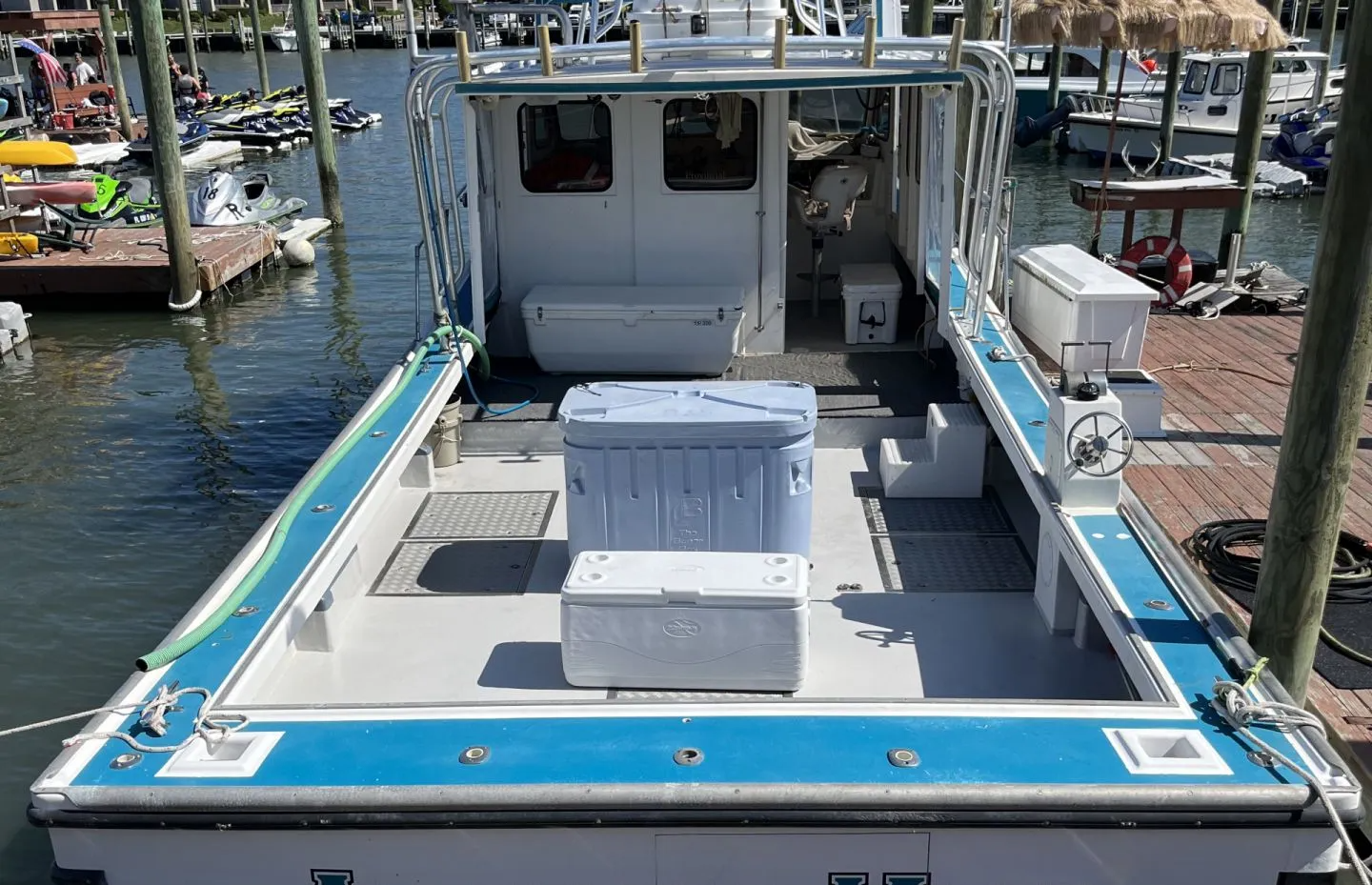 A boat is docked at a marina with a cooler on the deck.