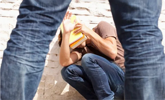 A man is kneeling down next to a girl who is holding a book.