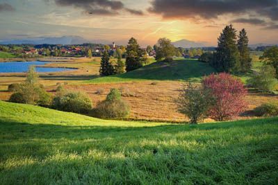 A sunset over a grassy field with trees and a lake in the background in Gray Tennessee