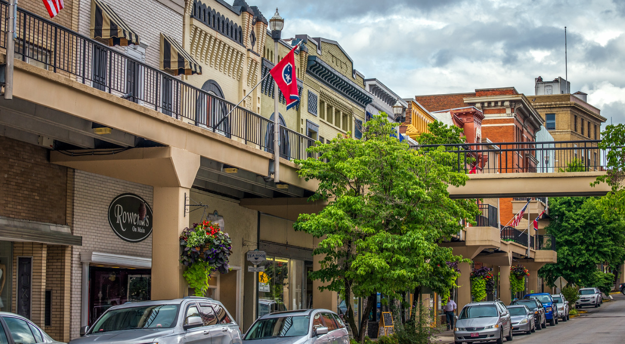 A city street with cars parked on the side of it and a bridge over it in downtown Morristown Tennessee