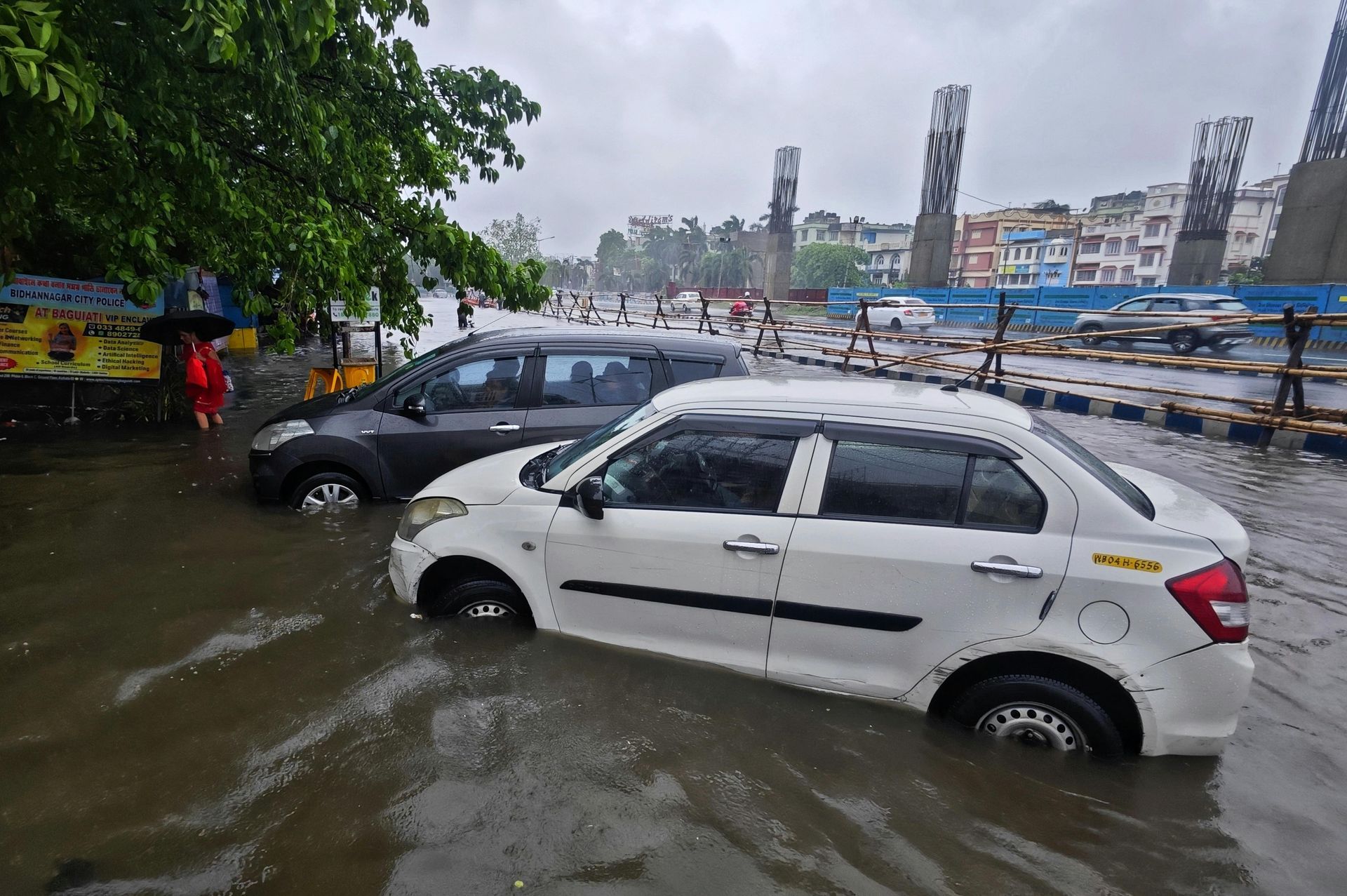 View Restoration Services Cars are submerged in floodwater on a city street. A grey sky and city in the background.