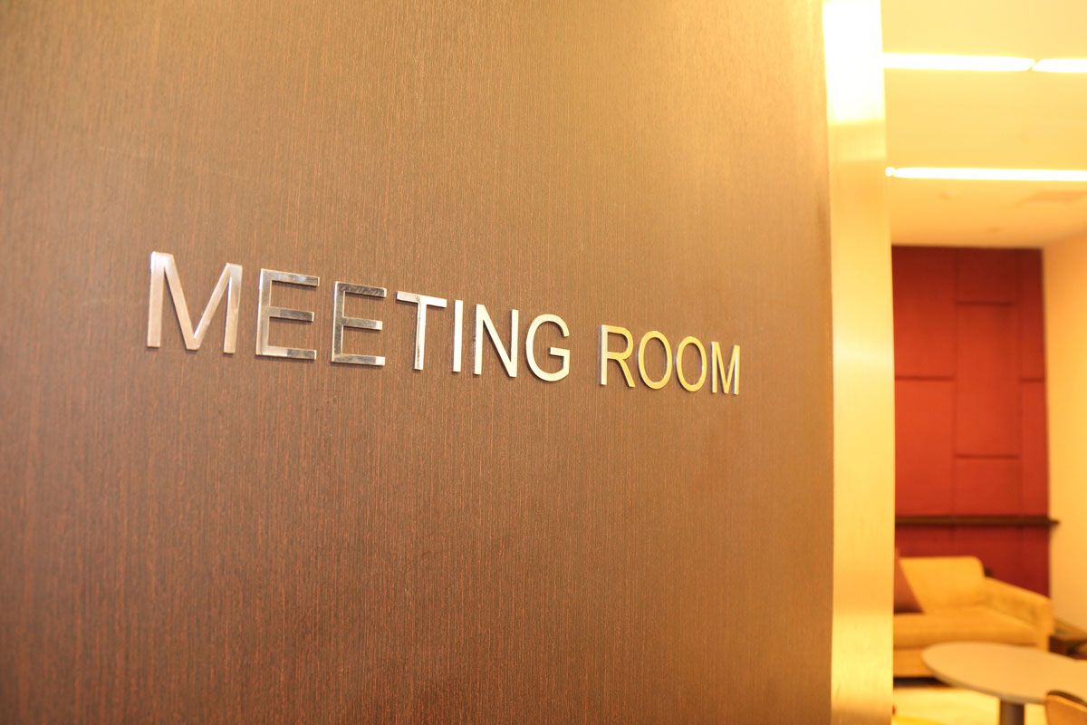 Meeting Room sign on a brown wall, with a partially visible waiting area.