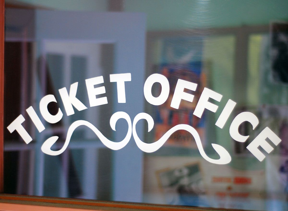 Ticket Office sign on glass window with decorative swirls.