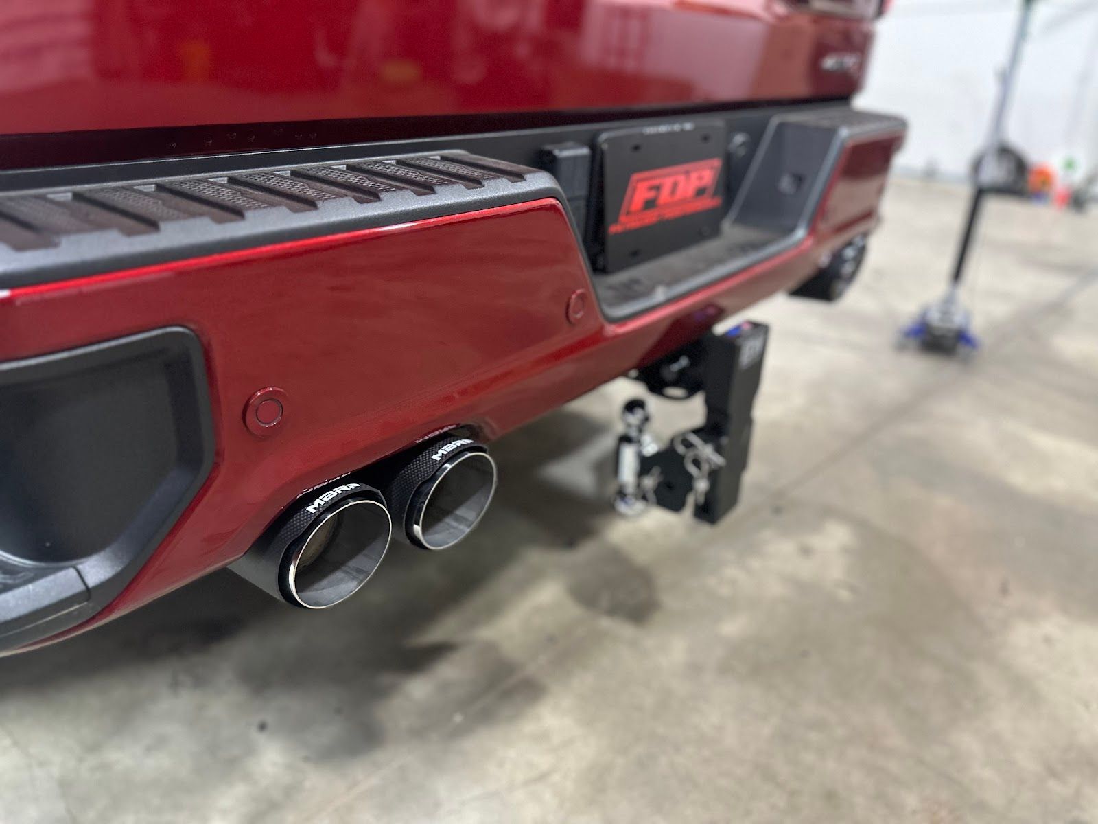 Red truck rear with dual exhaust pipes, a trailer hitch, and FDP license plate.