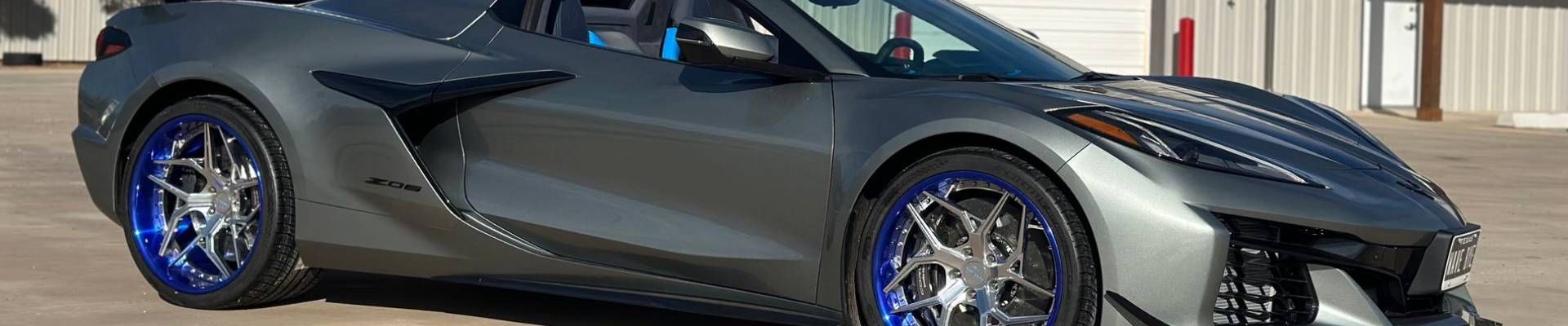 Gray sports car with blue rim accents on a paved surface.