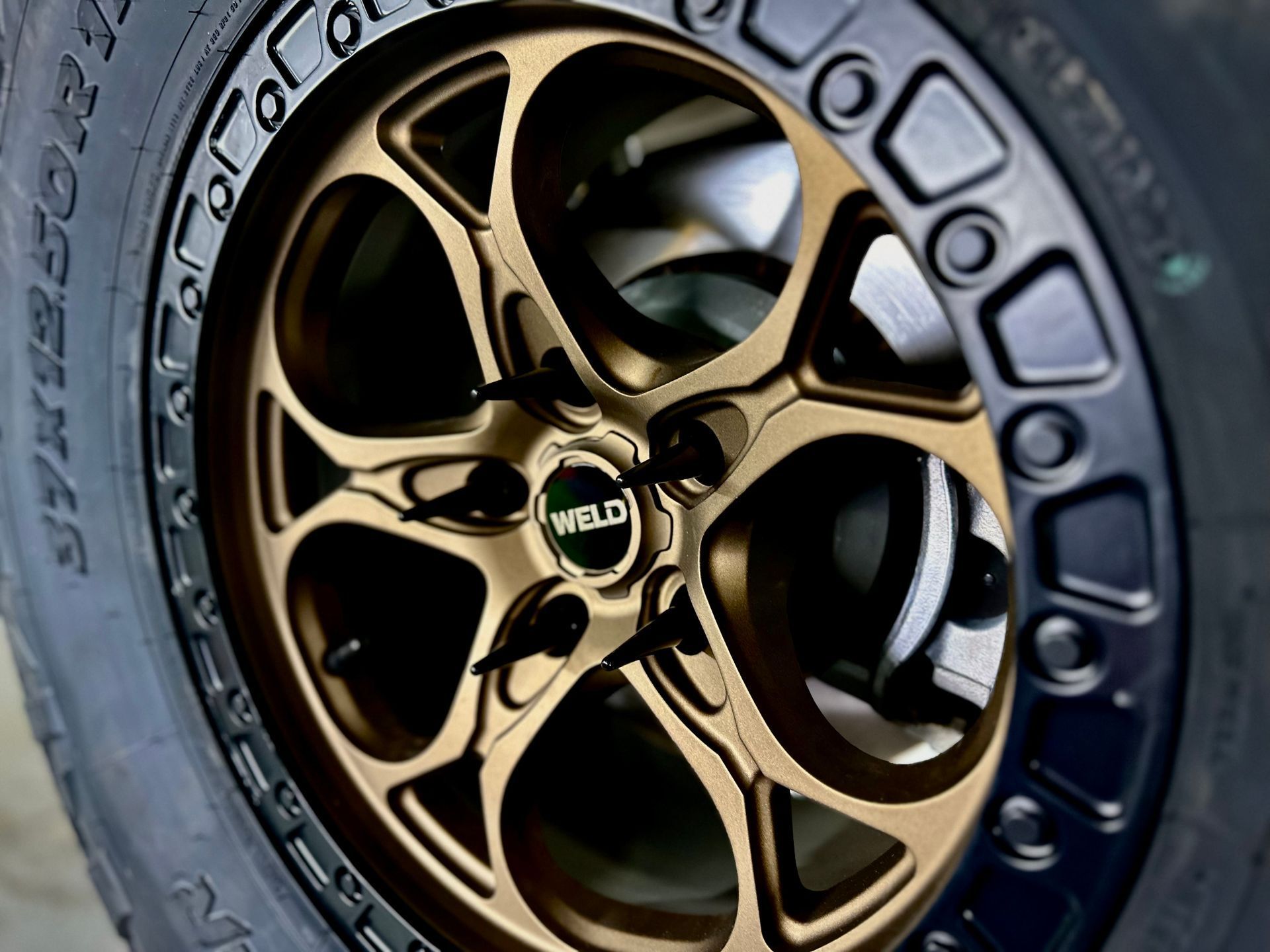 Bronze-colored WELD wheel with a black outer rim and tire. The wheel is mounted on a vehicle.