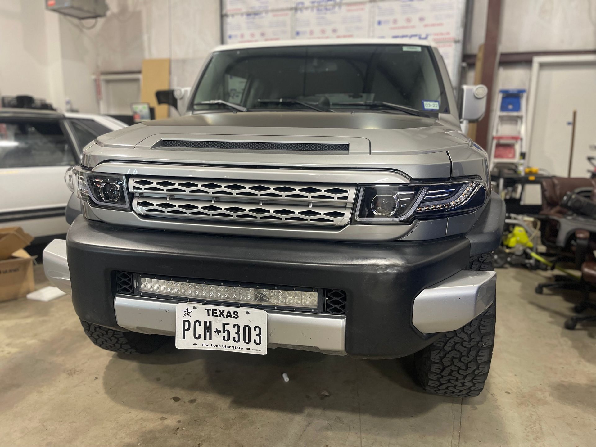 Gray and black modified Toyota FJ Cruiser with LED light bar and Texas license plate.