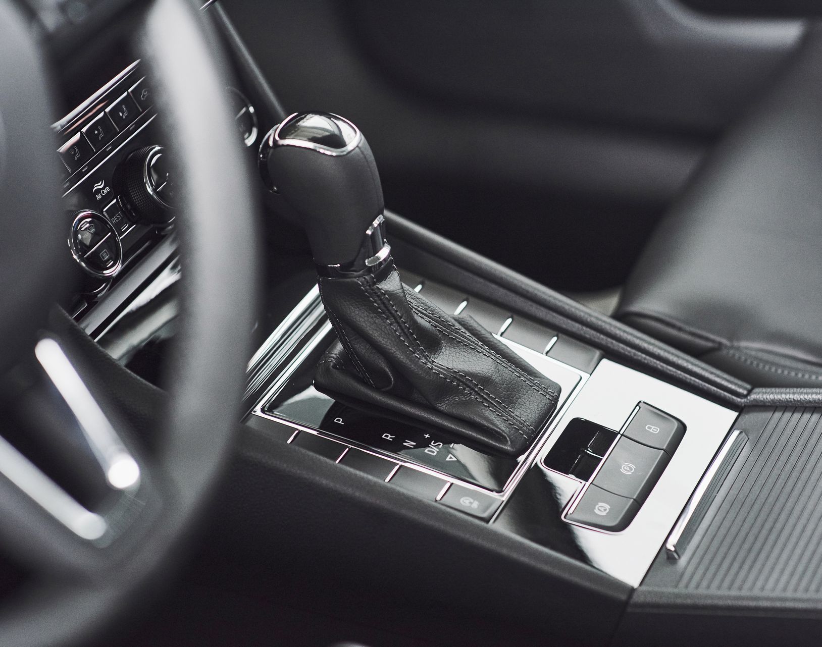 Car interior with gear shift lever and center console. Black and silver accents.