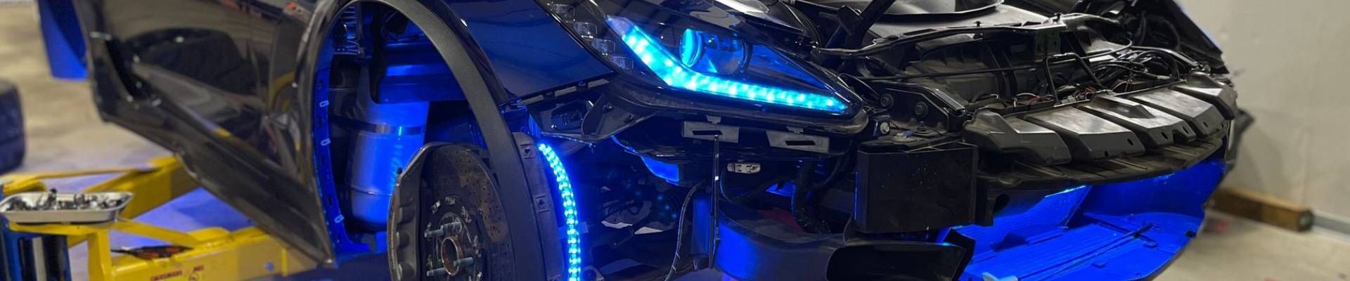 Front end of a black car with blue lights. The car is partially lifted. The lights are blue.