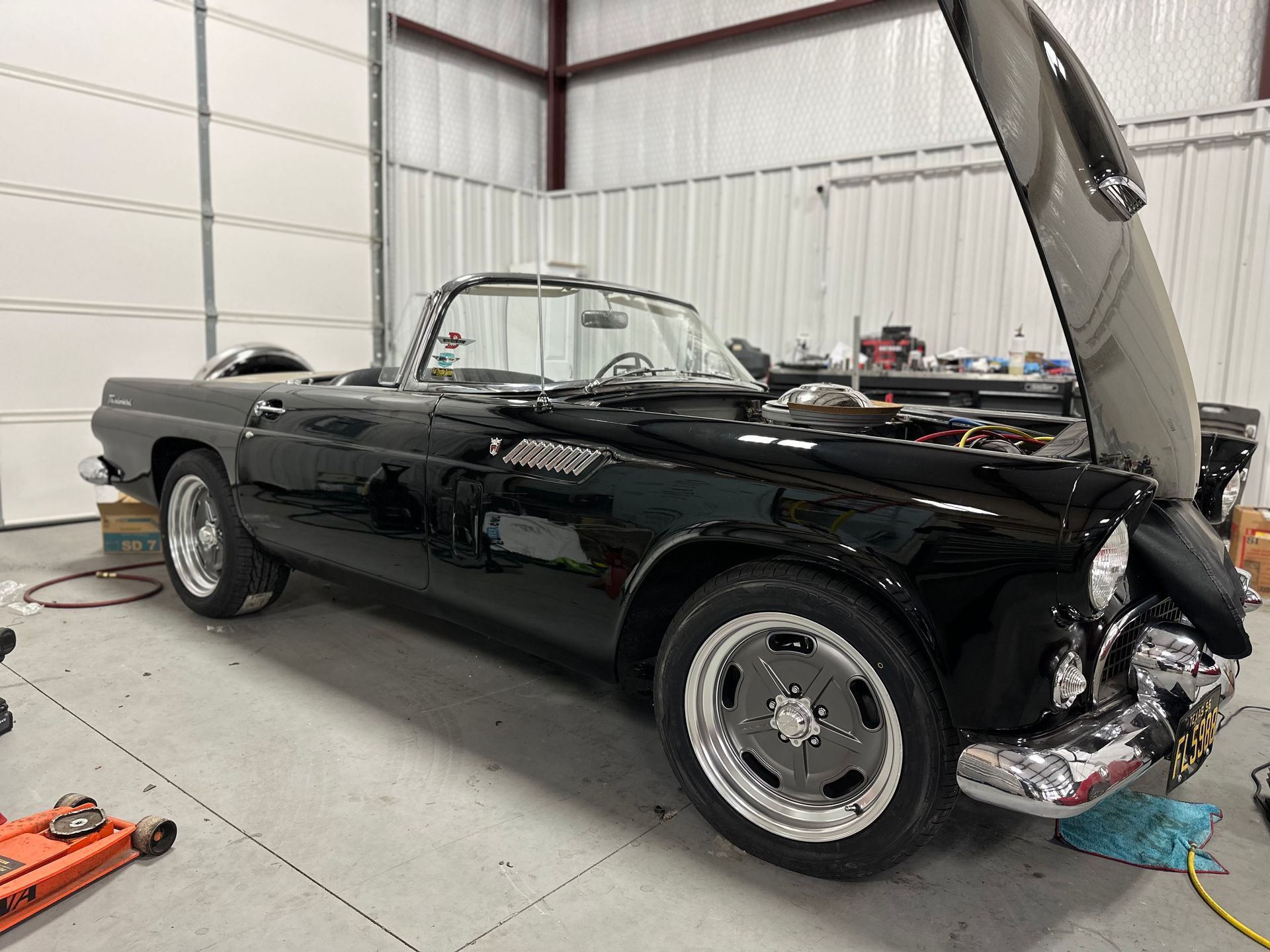 Black vintage convertible car with the hood open in a garage.