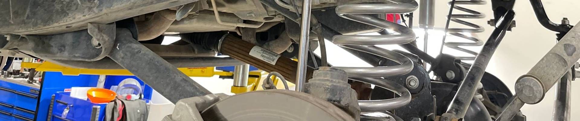 Undercarriage of a vehicle with a suspension system visible. Silver coil springs and a shock absorber are present.