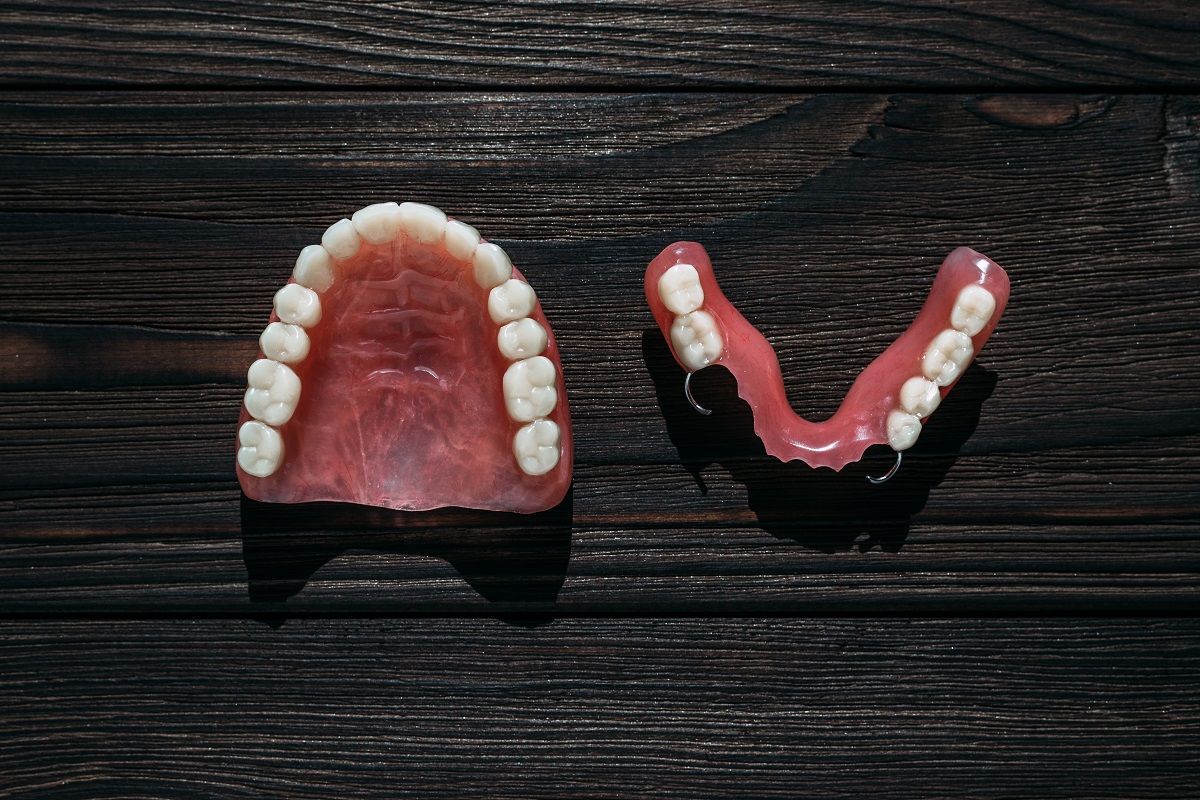 two partial dentures are sitting on a wooden table.