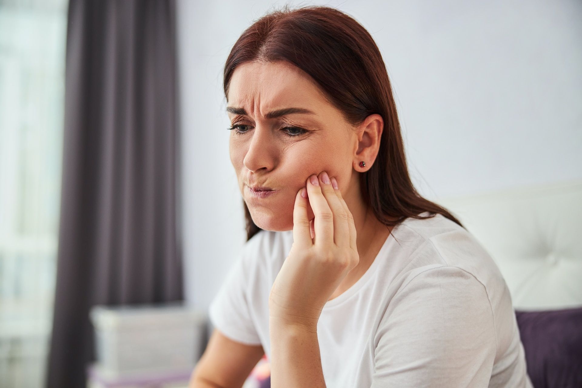 A woman holding the side of her face indicating tooth pain.