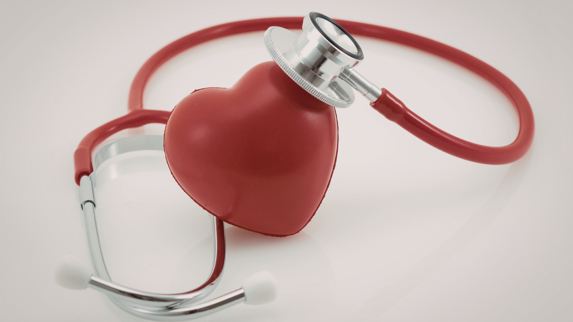 Smiling woman holding a glass of green smoothie by a window in a bright kitchen