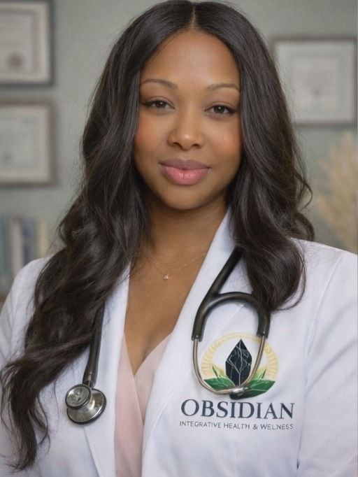 Doctor in a white coat with a stethoscope, smiling in a clinic office with framed certificates.