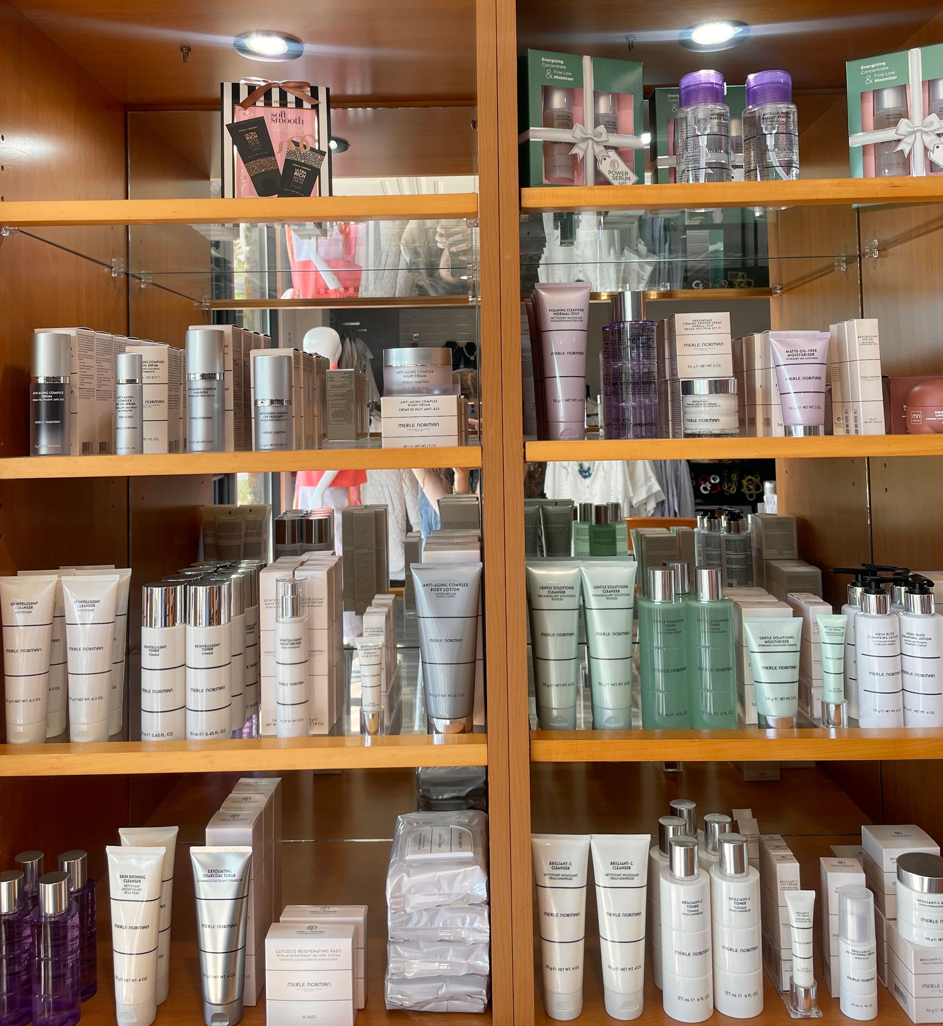 A makeup artist in a black apron applies blush with a brush to a bride in a white lace gown.