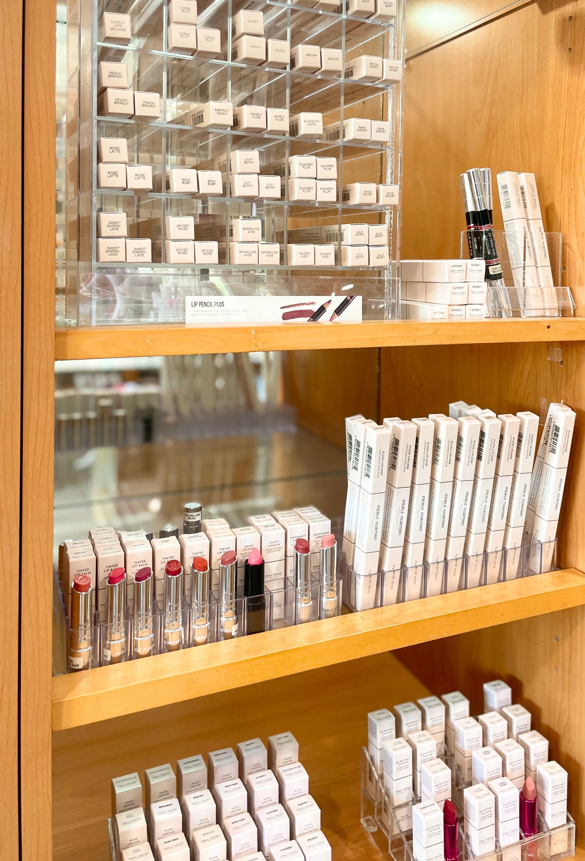 Makeup brushes with gold ferrules and black handles arranged on a white vanity with cosmetic products.