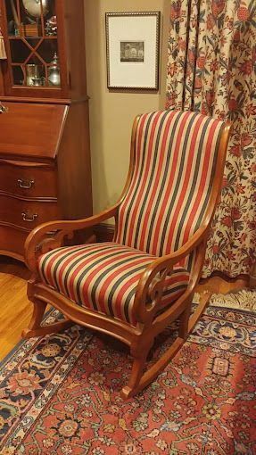A rocking chair is sitting on a rug in a living room.