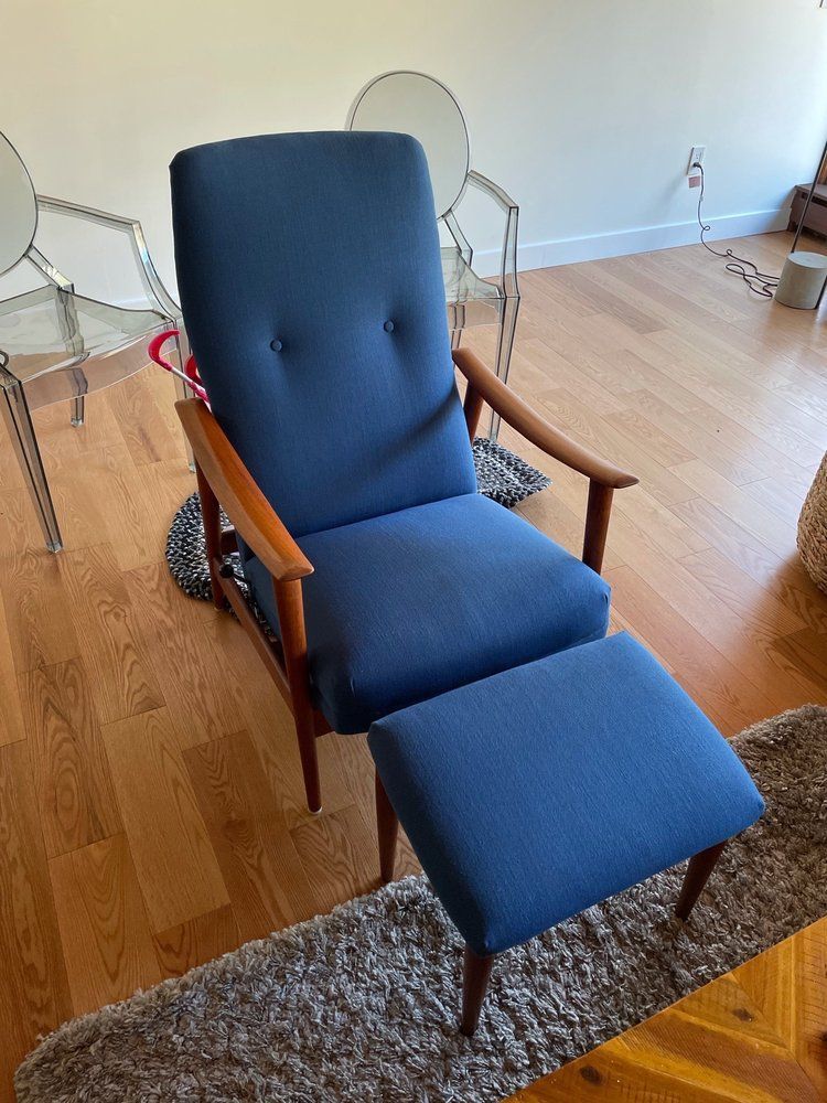 A blue chair and ottoman are in a living room.