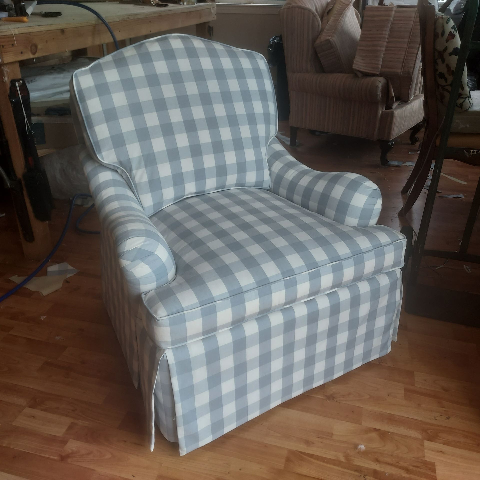 A blue and white checkered chair is sitting on a wooden floor.