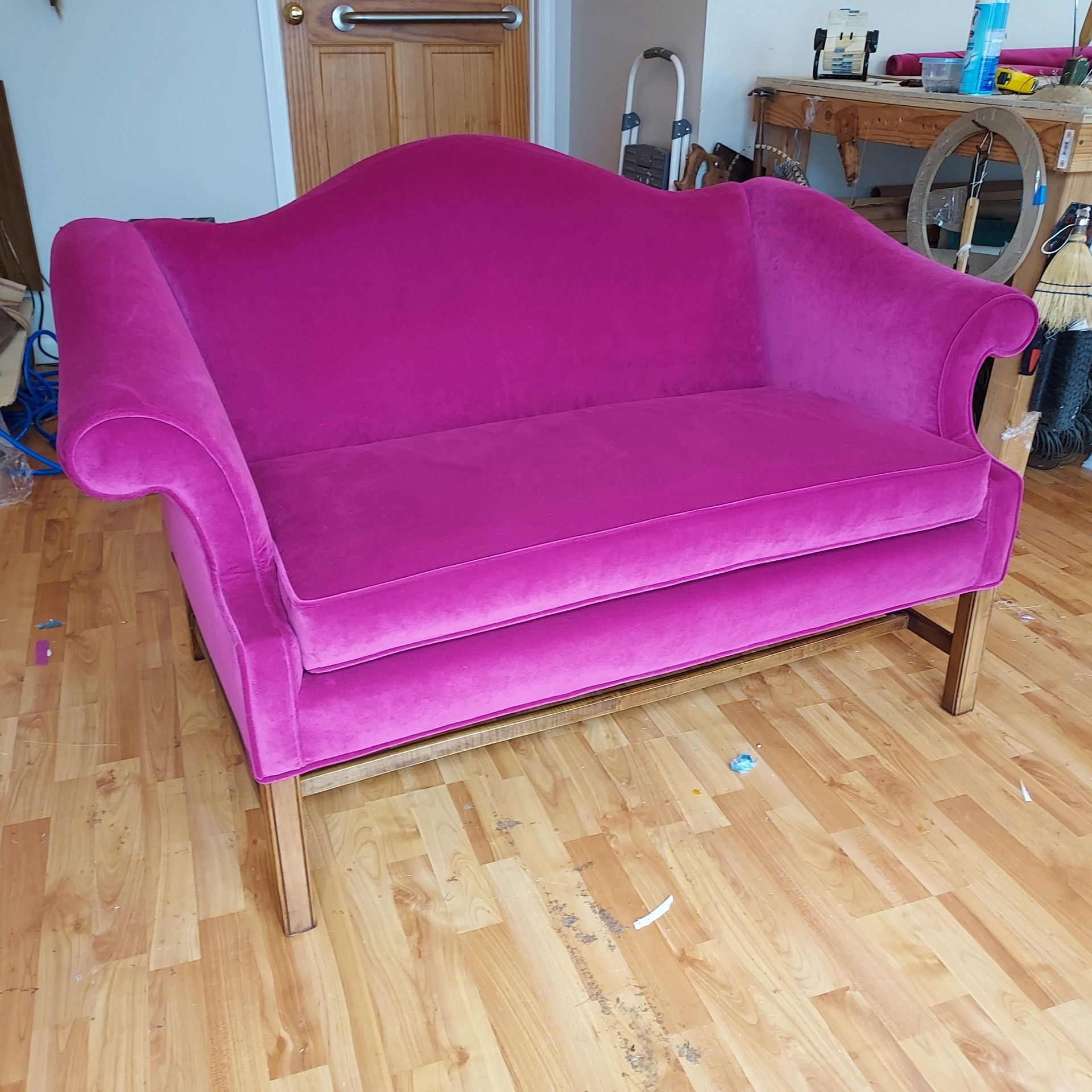 A pink couch is sitting on a wooden floor in a living room.