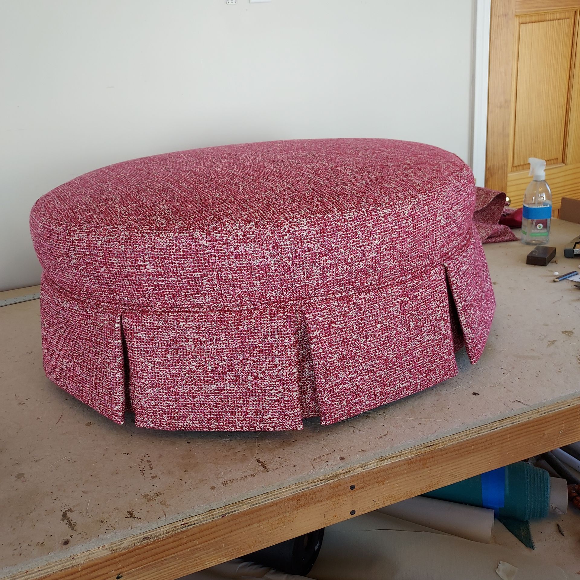 A pink ottoman is sitting on a wooden table
