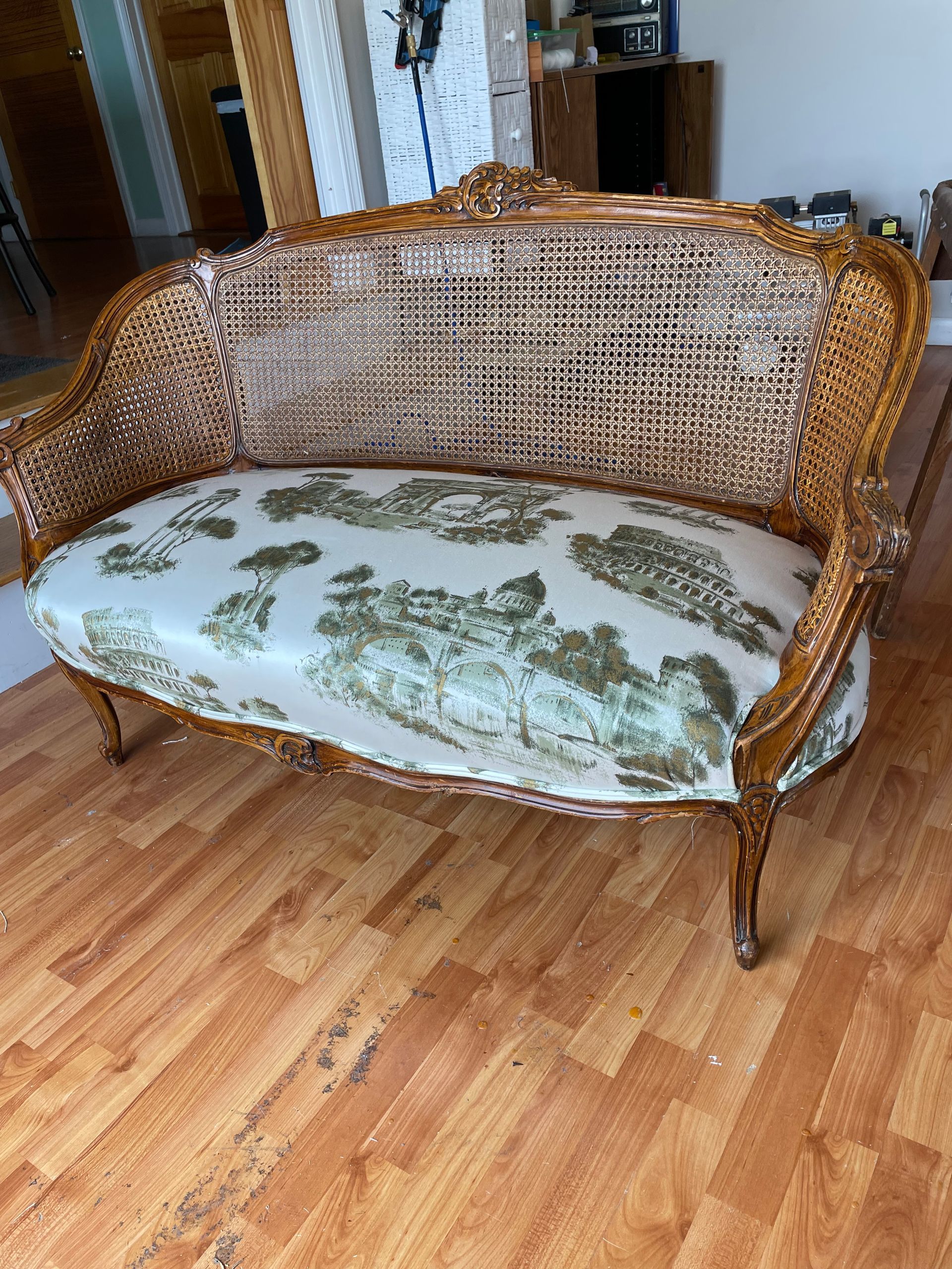 A wicker couch is sitting on a wooden floor in a living room.