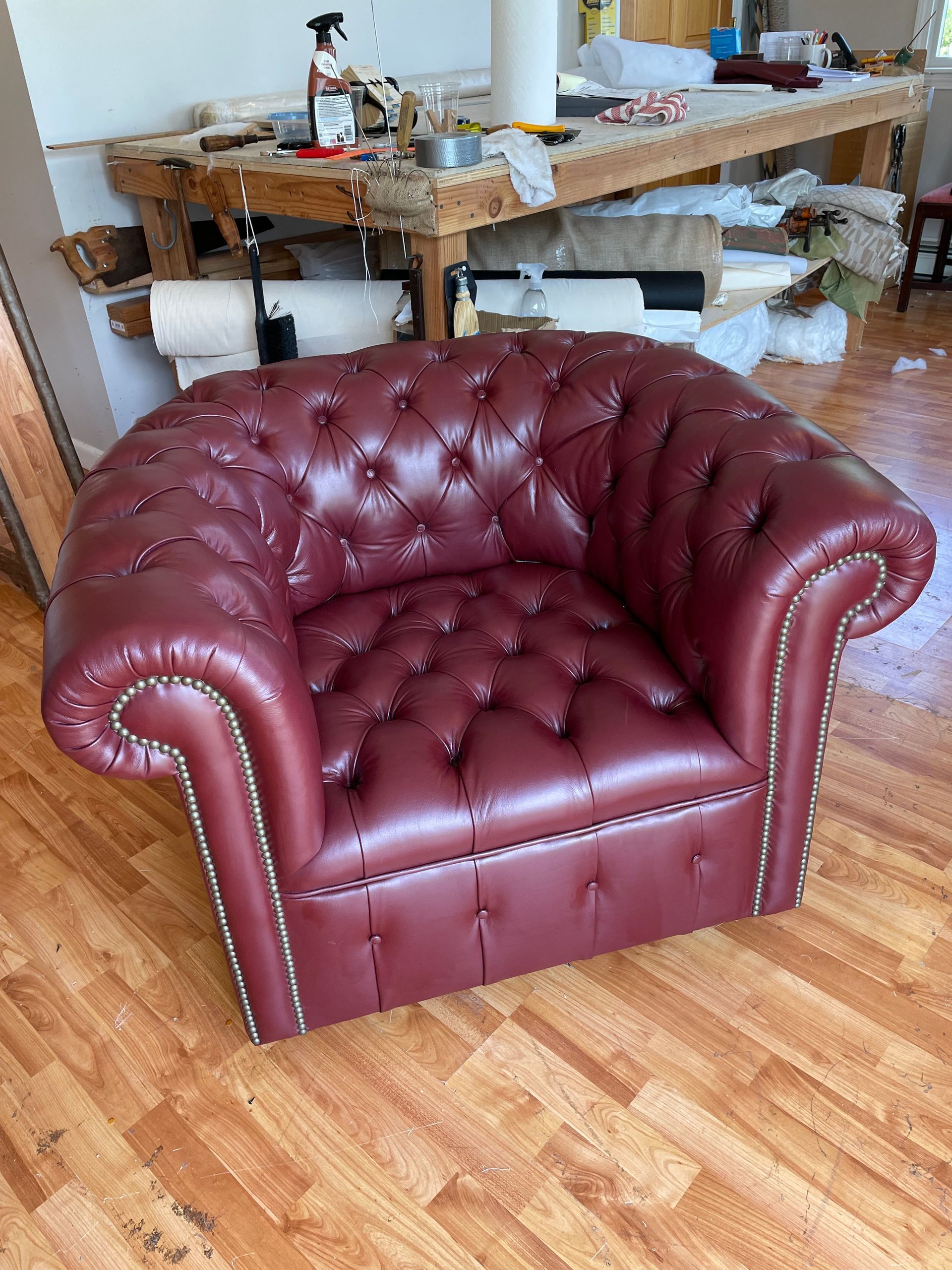 A red leather chair is sitting on a wooden floor in a room.