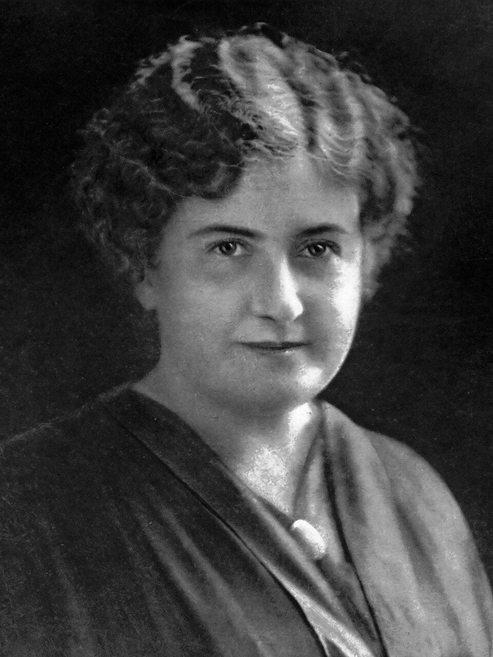 Black-and-white portrait of Maria Montessori with short curly hair, wearing a dark blouse