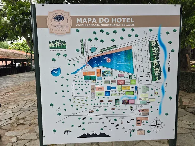 Placa de mapa do hotel mostrando o layout do resort com vários edifícios, uma grande piscina e área verde ao redor.
