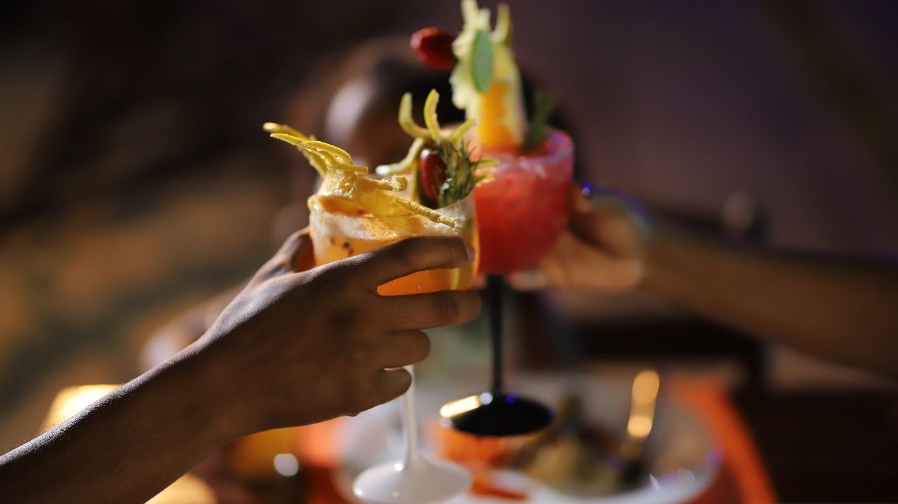 Duas pessoas brindando com coquetéis decorados com frutas.