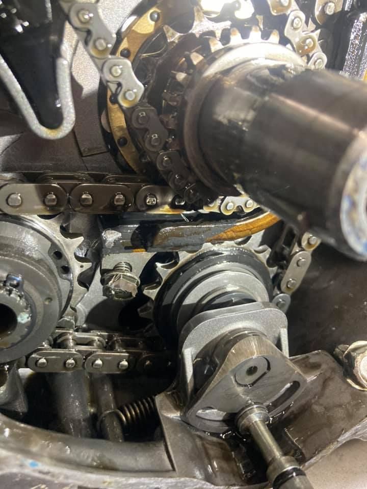 A close up of a chain on a motorcycle engine.