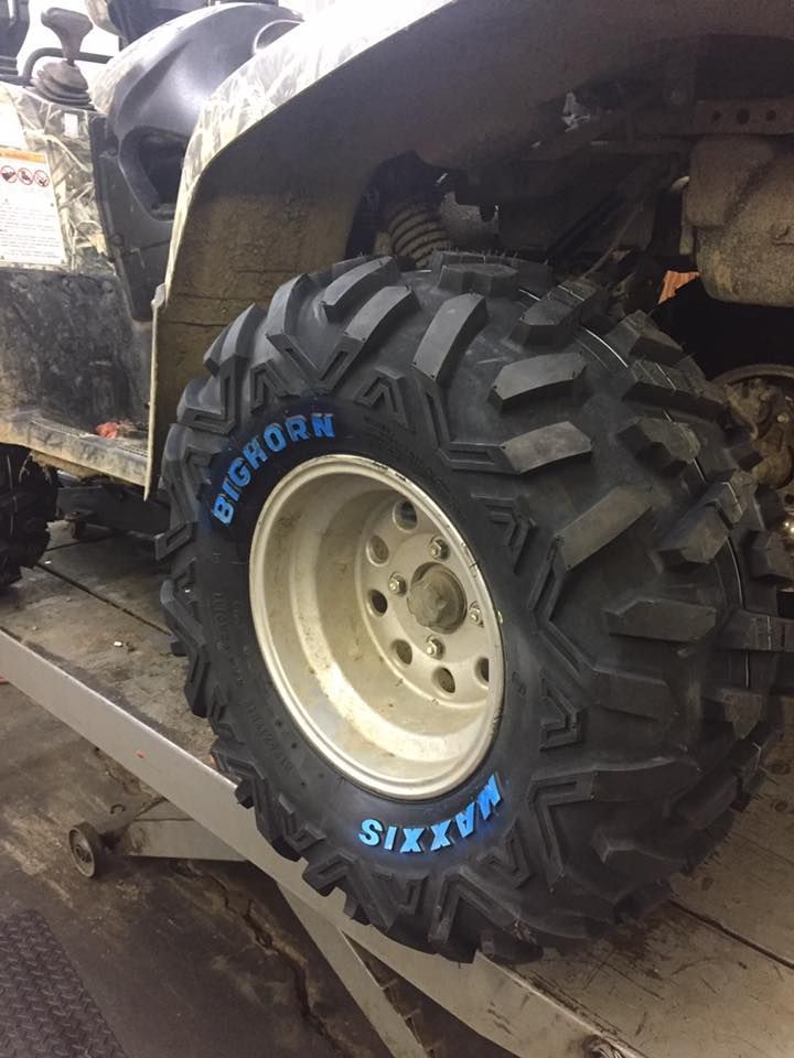 A close up of a tire on an atv on a lift.