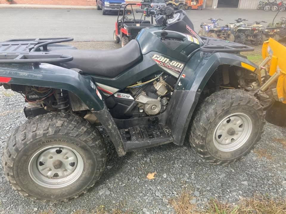 A can am atv is parked in a gravel lot.