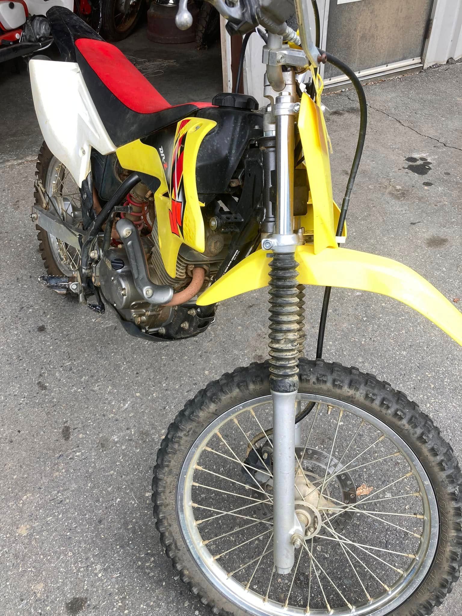 A yellow dirt bike is parked on the side of the road.