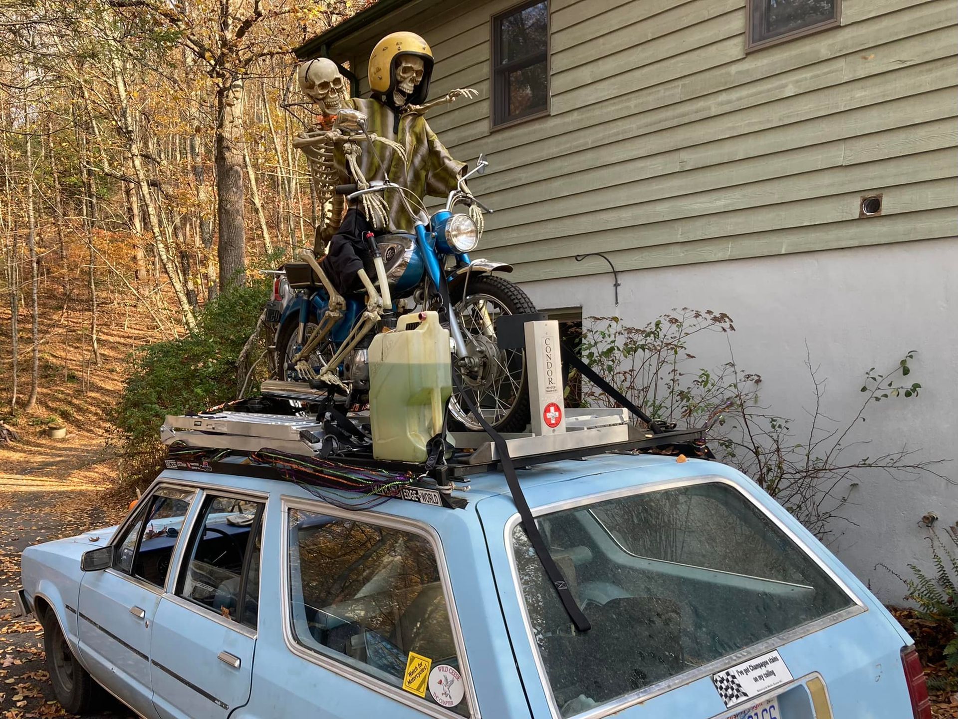 A blue car with a motorcycle on top of it
