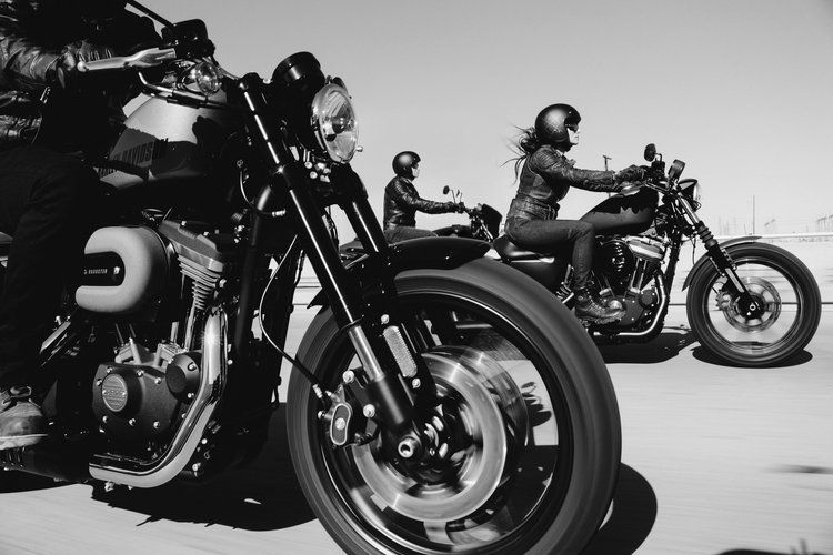 A black and white photo of three people riding motorcycles