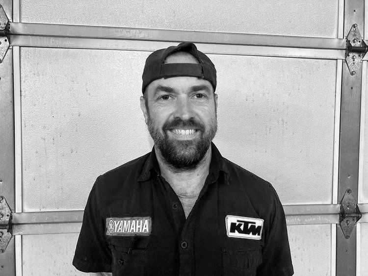 A black and white photo of a man wearing a hat and a yamaha shirt.