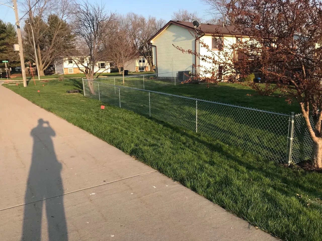 Shadow of a Person on the Sidewalk Next to a Chain Link Fence — Bondurant, IA — Titan Fence LLC