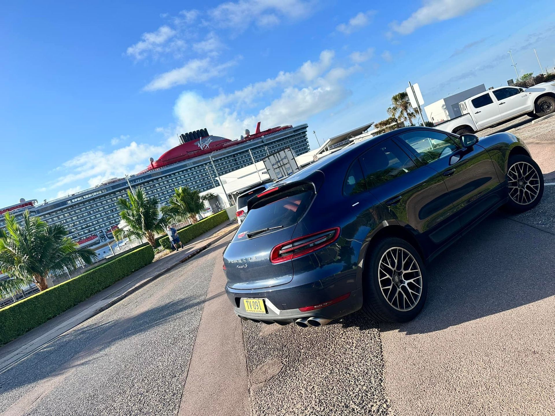 Dark gray Porsche Macan SUV parked on a gravel lot; a building and truck are in the background — Litchfield VIP Tours In Darwin City, NT