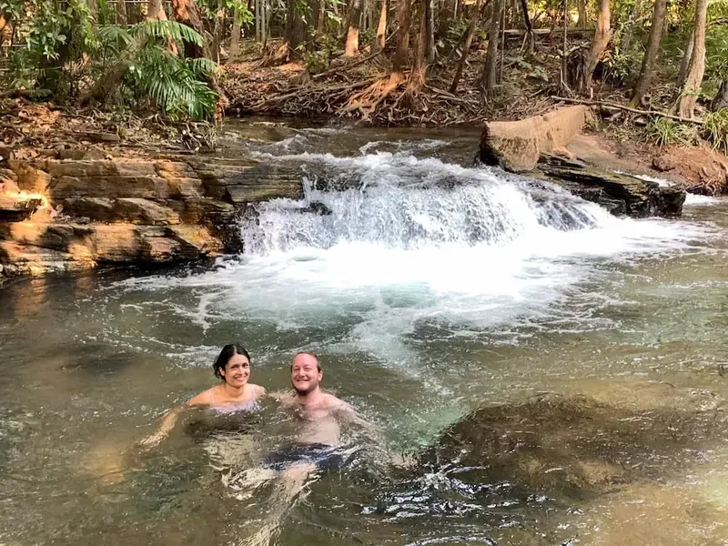 Couple Swimming in a Natural Pool With a Small Waterfall — Litchfield VIP Tours In Darwin City, NT